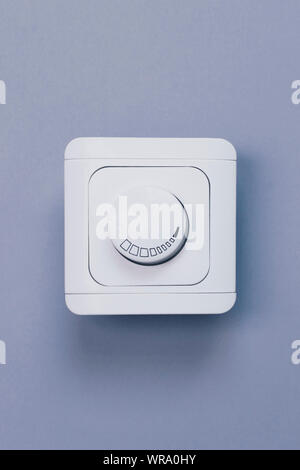 Dimmer Light Switch. Electrician switch. White rolling electricity switch on a bright wall Stock Photo