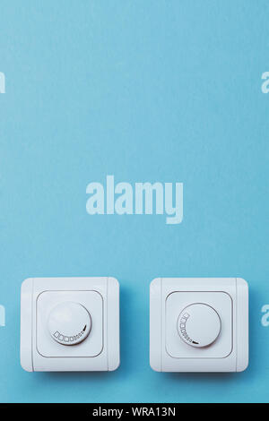Dimmer Light Switch. Electrician switch. White rolling electricity switch on a bright wall Stock Photo