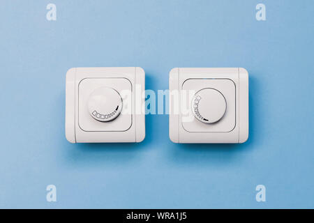 Dimmer Light Switch. Electrician switch. White rolling electricity switch on a bright wall Stock Photo
