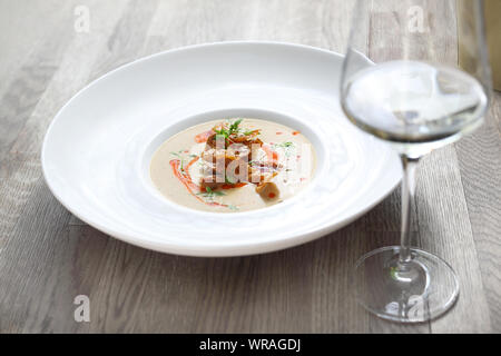 Creamy white vegetable soup with roasted potato chips. Stock Photo