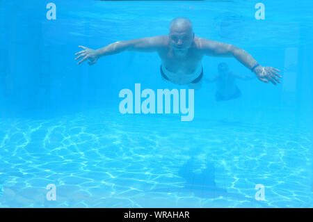 man swims underwater in a pool in his underpants. Leisure Stock Photo