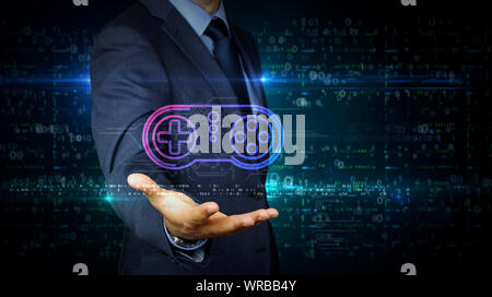 A businessman in a suit touch screen with game pad symbol hologram. Man using hand on virtual display interface. Gaming, 5G, play and online game futu Stock Photo