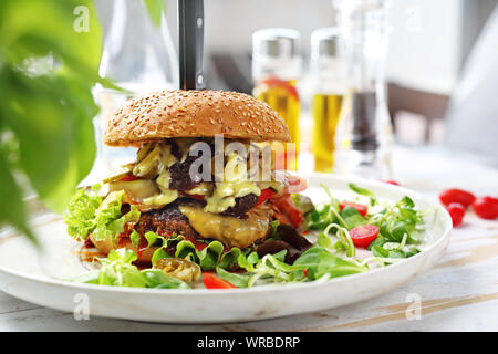 Cheeseburger with beef, bacon, cheese, vegetables served on a plate. Stock Photo