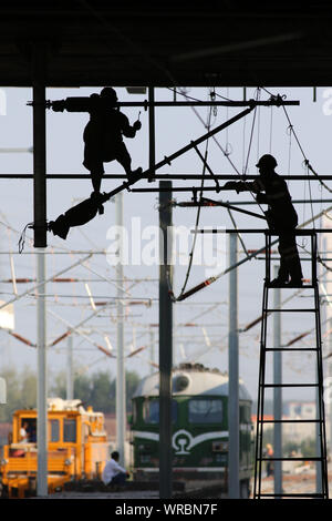 Chinese migrant workers mount electrified devices at the construction site of the Huai'an East Railway Station for high-speed railways in Huai'an City Stock Photo