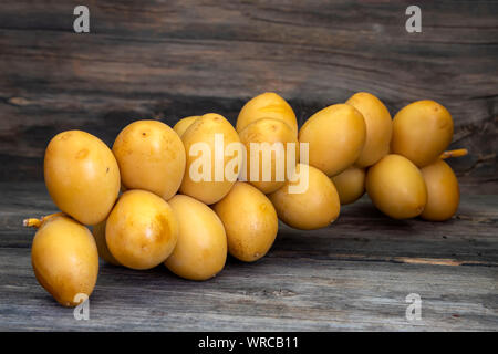 Sprig of ripe yellow dates close-up on a wooden table Stock Photo