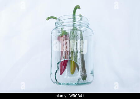 Three hot chili peppers in a broken jar Stock Photo