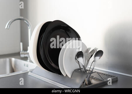 Set of fresh washed plates and cutlery on the kitchen gray table. Stock Photo