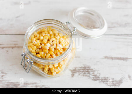 Canned sweet corn in glass jar on wooden table background. Stock Photo