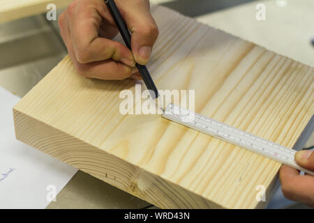 Female carpenter carpenter with scale meter stick. Ruler and pen render dimensions on wood in workshop Stock Photo