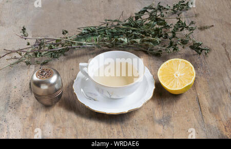 Cup of tea with mint and tea strainer on old wooden table, Stock Photo