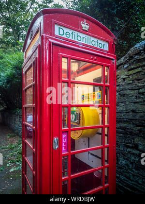 Traditional red telephone box in use as a defibrillator station in village. Stock Photo