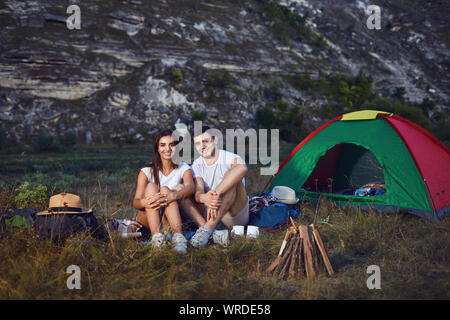 Romantic camping. A young couple sitting by the bonfire Stock Photo