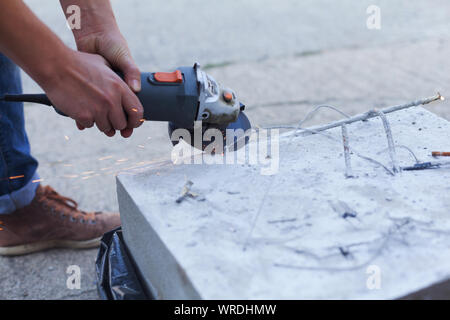 Woman separates metal with a cut-off wheel. One-handed angle grinder. Flex of concrete Stock Photo