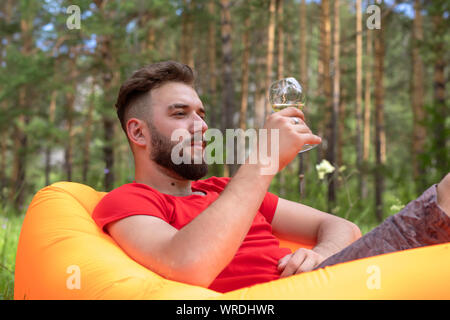 wine tasting, sommelier looks at a glass of wine. young bearded guy is resting outdoor and holding a glass with an alcoholic drink Stock Photo