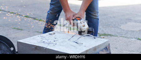Woman separates metal with a cut-off wheel. One-handed angle grinder. Flex of concrete Stock Photo