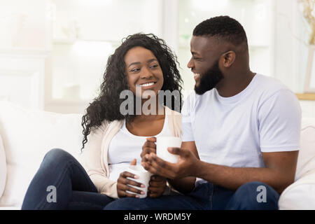 Loving millennial couple relaxing with cup of coffee at home Stock Photo