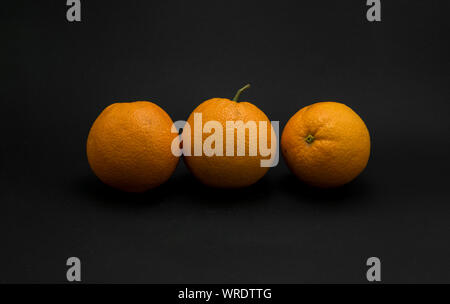 Three fresh oranges on black background. Stock Photo