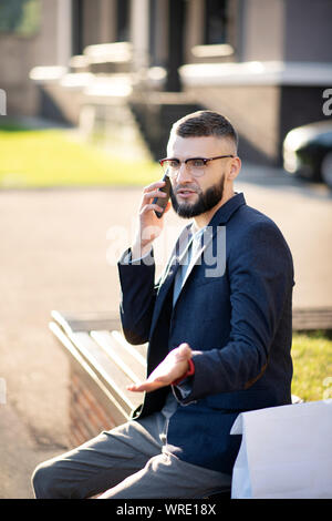 Bearded handsome businessman speaking with colleague by phone Stock Photo