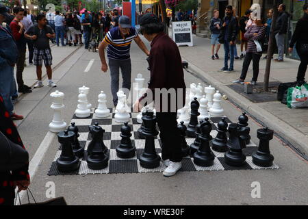 Two men play street chess on King Street West in Toronto during TIFF 2019 Stock Photo