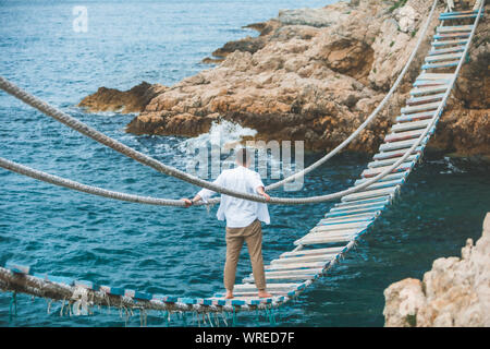 man walking by suspension bridge cross sea bay Stock Photo