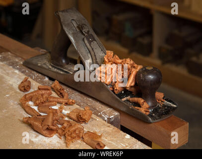 A wood plane with mahogany wood shavings on a carpenters work bench. Stock Photo