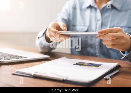Woman using smartphone in horizontal orientation taking photo of documents Stock Photo