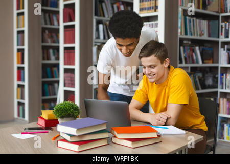Smart black guy helping his classmate with homework Stock Photo