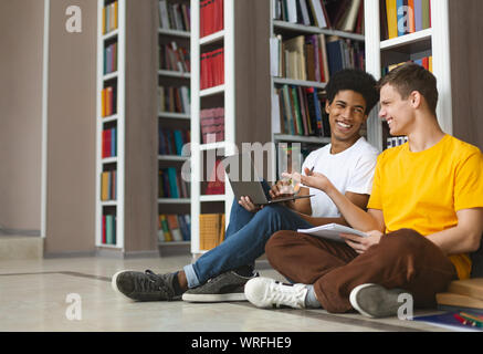 Two young guys having fun while studying at library Stock Photo