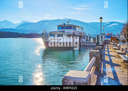 ST WOLFGANG, AUSTRIA - FEBRUARY 23, 2019: Relax in small park on embankment of Wolfgangsee lake with small benches, old-styled streetlights and ferry Stock Photo