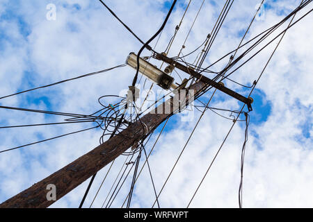 Wooden electric pole with wires and street light against cloudy blue sky Stock Photo