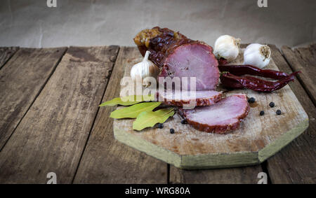Dried pork meat with chilli peppers, black pepper , garlic and bay leafs on old wooden table Stock Photo