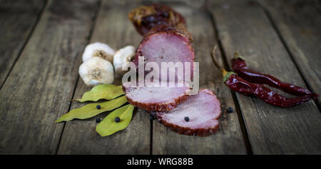 Dried pork meat with chilli peppers, black pepper , garlic and bay leafs on old wooden table Stock Photo