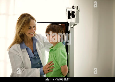 Doctor measuring a young boy's height. Stock Photo