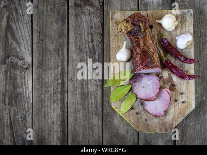 Dried pork meat with chilli peppers, black pepper , garlic and bay leafs on old wooden table. High angle view, with space for text. Stock Photo