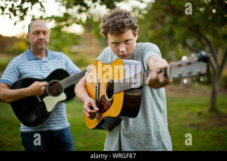 Portrait of a father and son practicing playing guitar together. Stock Photo