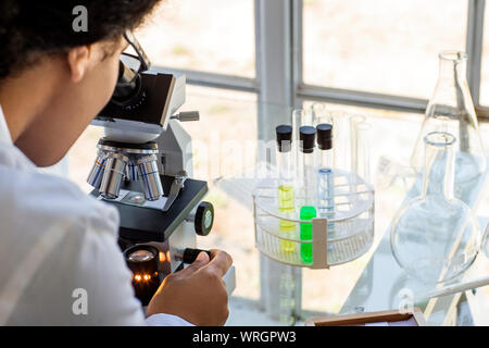Scientist looking through a microscope at a sample. Stock Photo