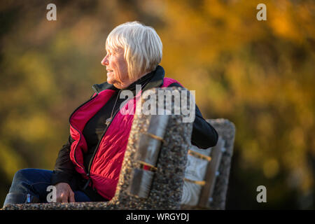 Senior woman sitting on bench. Stock Photo