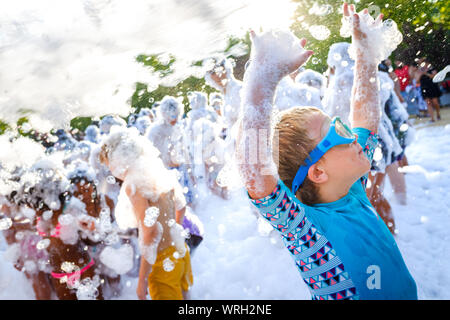 Kids having fun at a soap foam party. Stock Photo