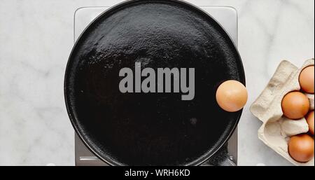 Animation of an egg frying itself in a hot pan jumping from a carton to the edge as butters melts then breaking itself open and frying before being tu Stock Photo