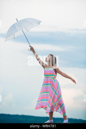 I believe i can fly. Touch sky. Girl with light umbrella. Fairy tale character. Happy childhood. Feeling light. Anti gravitation. Fly drop parachute. Dreaming about first flight. Kid pretending fly. Stock Photo