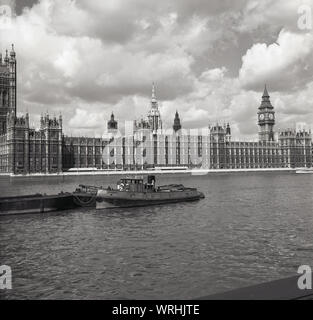 1950s, historical, a view across the river Thames, showing a barge on a mooring and the Palace of Westminster, where the two of Houses of Parliament function, the seat of the UK Government, Westminster, London, England, UK. Stock Photo