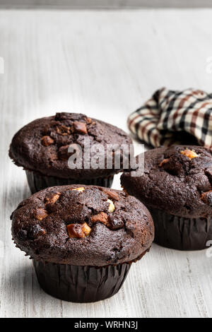 Three  chocolate muffins on the rustic table with cloth napkin Stock Photo