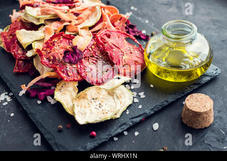 Healthy homemade vegetable chips from beetroot, tomatoes, carrot and zucchini on black background. Organic diet food. The vegan diet. Dried vegetables Stock Photo