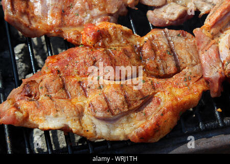 Pork neck getting grilled on open fire Stock Photo