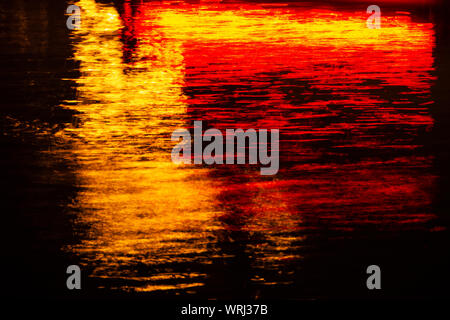 Multi colored neon lights reflected in rippling water. Stock Photo