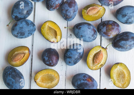 Fresh and ripped delicious plums on old white wooden table. High angle view Stock Photo