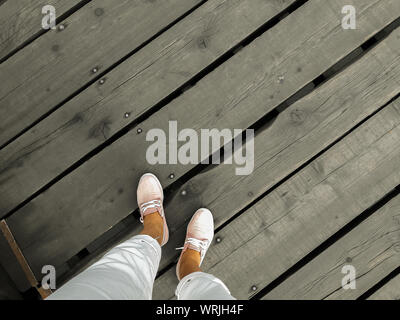 Personal perspective of woman legs standing on wooden floor, space for text Stock Photo