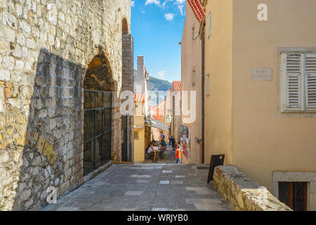 Tourists enjoy a meal at a sidewalk cafe on one of the narrow alleys inside the ancient walled city of Dubrovnik, Croatia. Stock Photo