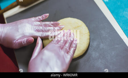 sculpt from dough buns and bread. the woman kneads the dough and makes round bread from it. A cook in gloves creates a tasty bakery product. Stock Photo