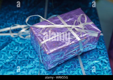 blue square gift box with shiny satin bow on gray . shiny classic blue gift box . Stock Photo